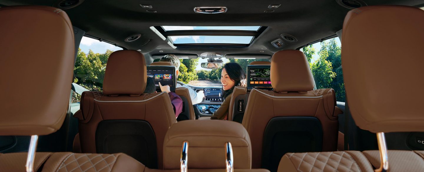 The front passenger in the 2024 Chrysler Pacifica Pinnacle turning around to look at a child in the second row driver-side seat.