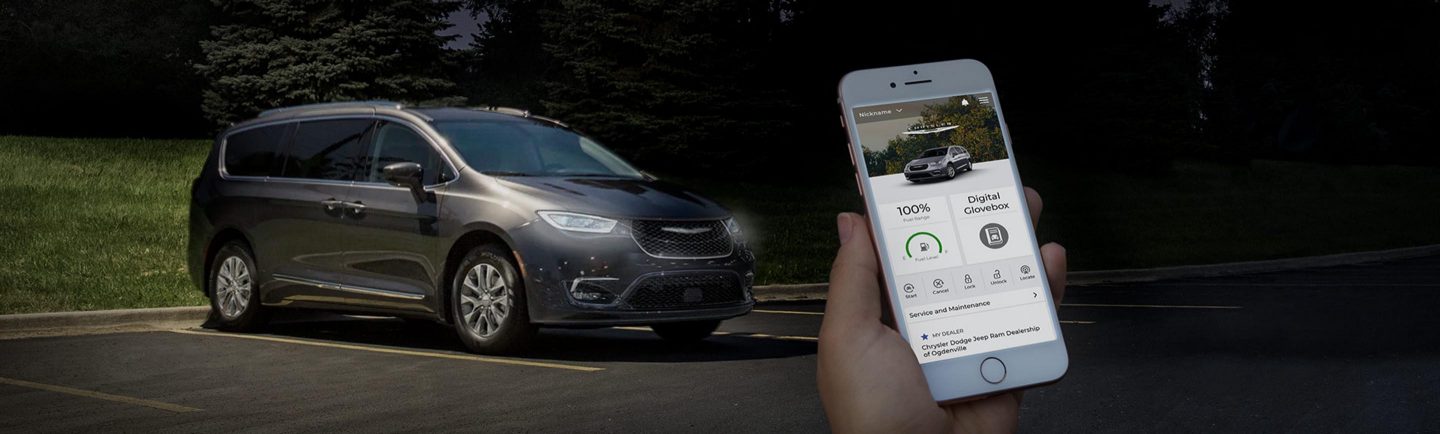 A person holding a smartphone displaying the SiriusXM Guardian app with a Chrysler Pacifica in the background.